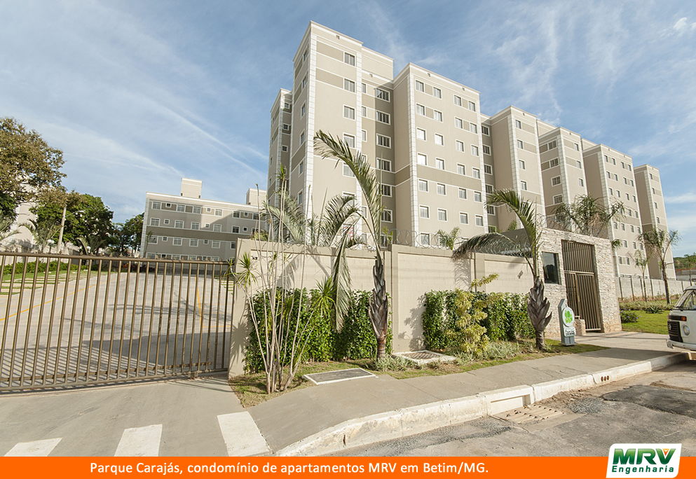 Fachada do condomínio da MRV Parque Carajás, com paredes em tons bege, portões marrom com os apartamentos ao fundo 