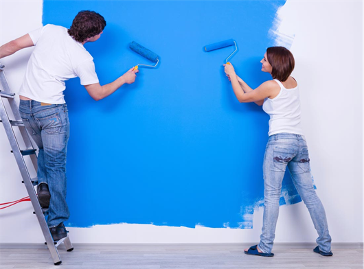 Casal pintando a parede do apartamento de azul
