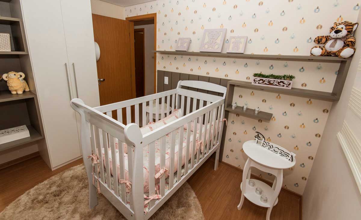 Quarto de bebê com berço branco, prateleiras em tons escuros, guarda-ropa branco com prateleiras e mesa de cabeceira branca.