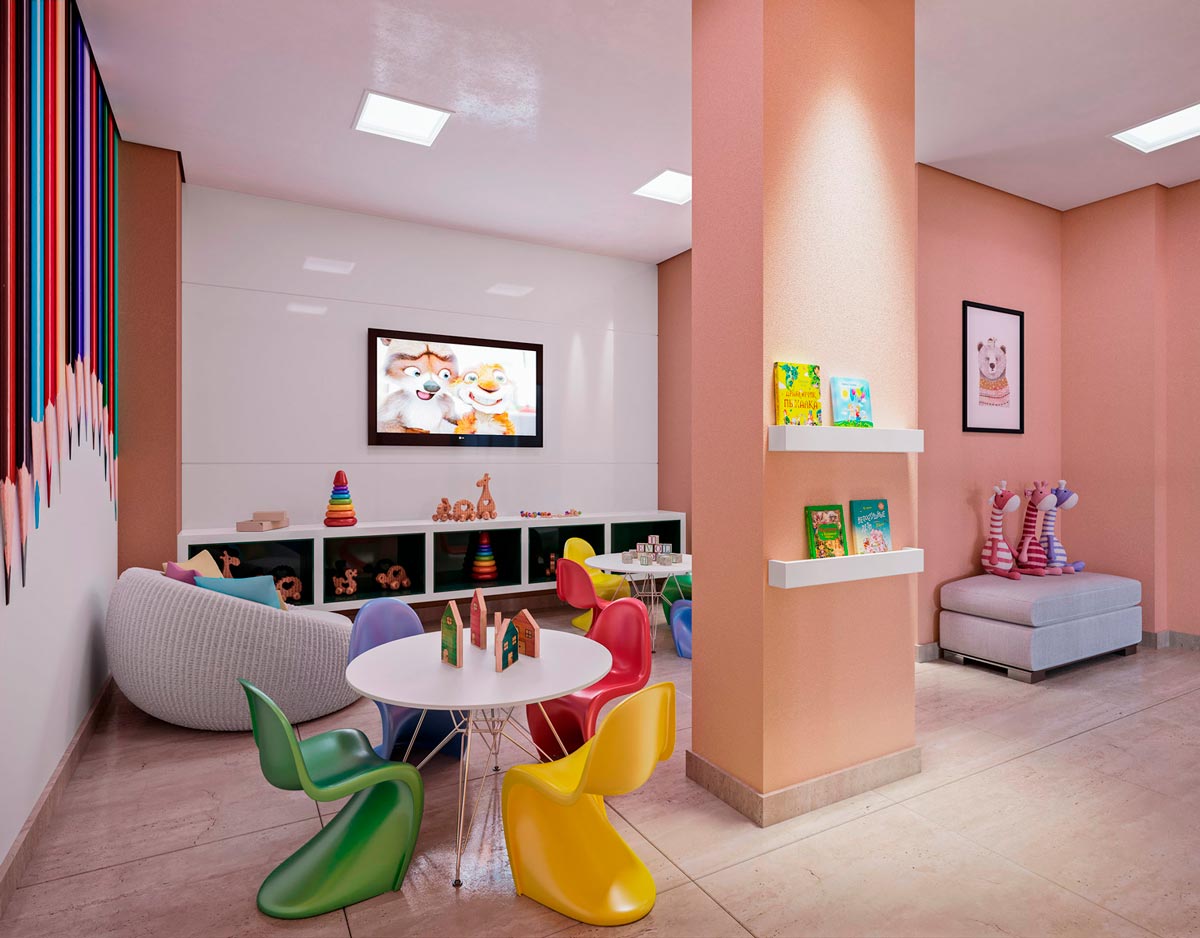 Sala com mesa e cadeiras coloridas, móvel com brinquedos, prateleiras com livros, pufes com almofada, televisão e quadros.