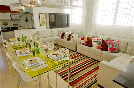 Sala decorada de apartamento da MRV com tapete e almofadas em cores vibrantes e sofá neutro