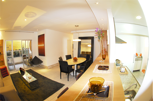Sala ampla de apartamento da MRV decorada com luzes amareladas e tons em tabaco